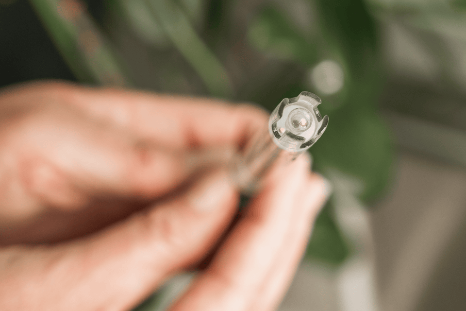 Hand holding a clear glass pH Probe with a blurred green background